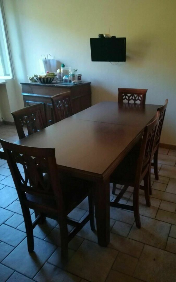 Tavolo fratino allungabile in legno noce con sedie lavorate in un ambiente cucina.